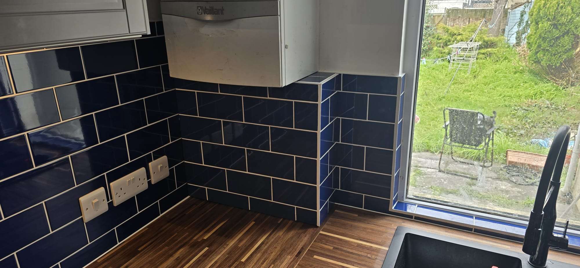 Tiled box fitted over under-boiler pipework, blending in with surrounding wall for a clean, professional finish